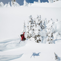 A freeskier takes off from a jump in the backcountry of Sun Peaks Resort, near Kamloops BC. In the air, he has his skis crossed in a trick known as 