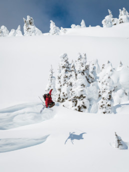 A freeskier takes off from a jump in the backcountry of Sun Peaks Resort, near Kamloops BC. In the air, he has his skis crossed in a trick known as 
