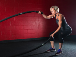 A female fitness enthusiast trains at the Kororis Acceleration facility in Kamloops, BC. In the photo, she uses battle ropes for a high intensity cardio workout.