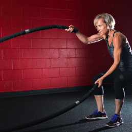 A female fitness enthusiast trains at the Kororis Acceleration facility in Kamloops, BC. In the photo, she uses battle ropes for a high intensity cardio workout.