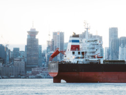 A tanker ship is visible floating in Coal Harbour at the Port of Vancouver. The downtown Vancouver skyline is visible in the background.