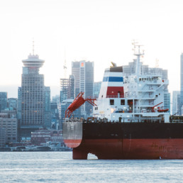 A tanker ship is visible floating in Coal Harbour at the Port of Vancouver. The downtown Vancouver skyline is visible in the background.