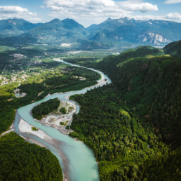 Squamish River winds through the valley towards Howe Sound. The city of Squamish is visible in the background, as is the Stawamus Chief