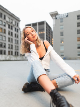 A young woman strikes a casual pose at a photoshoot location in downtown Vancouver. Old buildings surround the location with their architectural details visible.