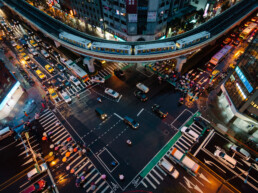 A photo taken from a Taipei rooftop looking down at a busy intersection. A Taipei MRT train and many colourful umbrellas of pedestrians crossing the intersection are visible.